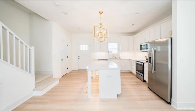 kitchen featuring white cabinets, stainless steel appliances, a kitchen breakfast bar, a chandelier, and a kitchen island