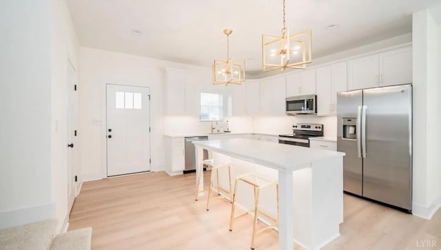 kitchen with stainless steel appliances, a center island, tasteful backsplash, light wood-type flooring, and a notable chandelier