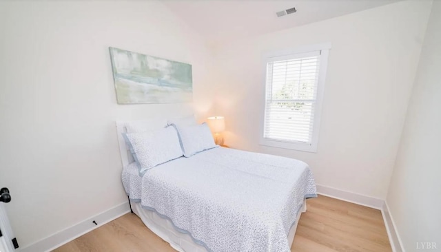 bedroom with baseboards, light wood finished floors, and visible vents