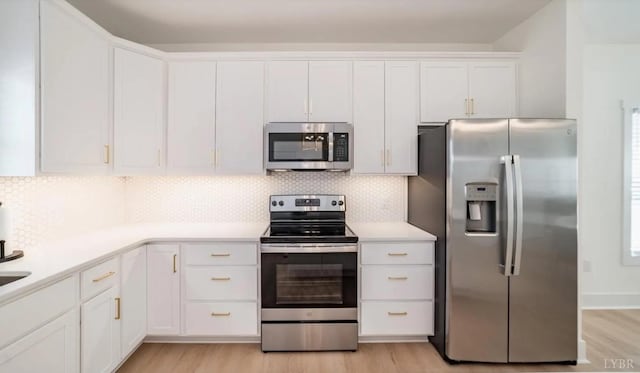 kitchen with white cabinets, light countertops, light wood-type flooring, and stainless steel appliances