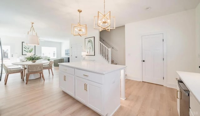 kitchen featuring light countertops, light wood-type flooring, a notable chandelier, dishwasher, and a kitchen island
