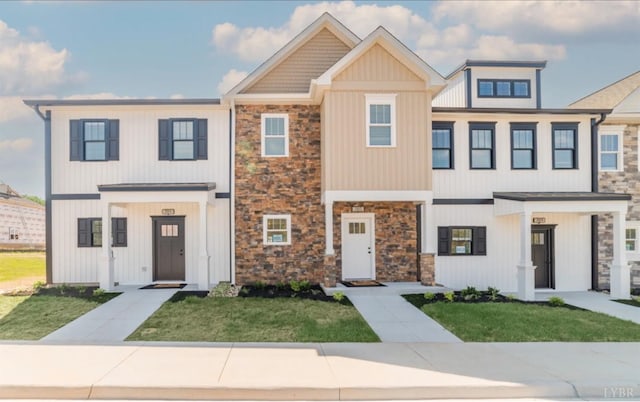multi unit property with a front lawn and stone siding