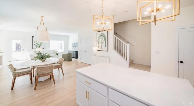 kitchen featuring white cabinets, light countertops, light wood-style flooring, open floor plan, and a notable chandelier