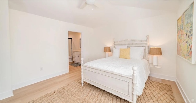 bedroom featuring baseboards, ensuite bath, wood finished floors, and a ceiling fan