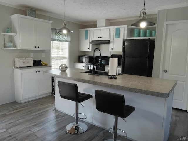 839 Cedar Gate Rd, Monroe, VA 24574 - kitchen with freestanding refrigerator, open shelves, white cabinets, under cabinet range hood, and a breakfast bar