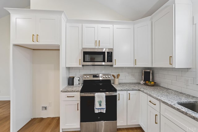 893 Cedar Gate Rd, Monroe, VA 24574 - kitchen featuring appliances with stainless steel finishes, light wood-type flooring, backsplash, white cabinets, and vaulted ceiling