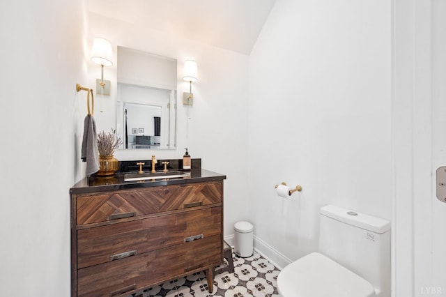 bathroom featuring toilet, baseboards, tile patterned flooring, vaulted ceiling, and vanity