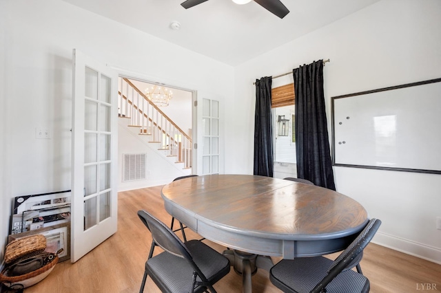 dining area featuring french doors, visible vents, ceiling fan with notable chandelier, stairway, and light wood-type flooring