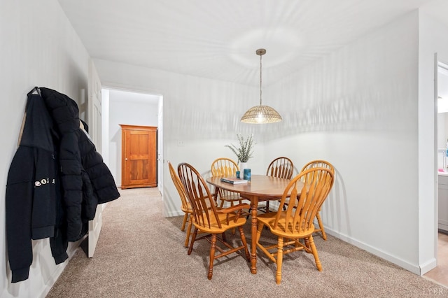 dining area featuring light carpet and baseboards