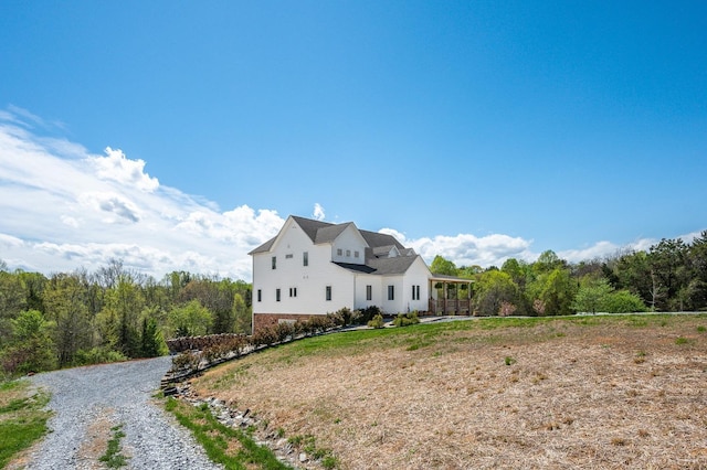 view of front of property featuring a wooded view, brick siding, and driveway