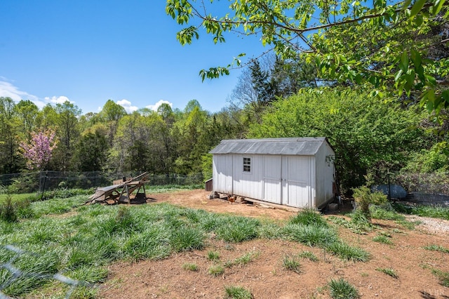 view of shed featuring a wooded view and fence