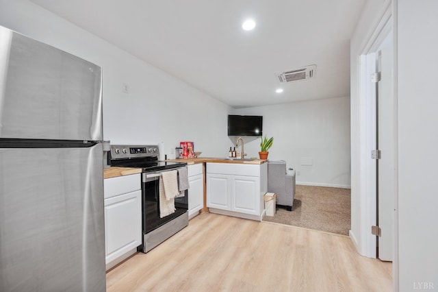 kitchen featuring stainless steel appliances, white cabinets, visible vents, and a sink