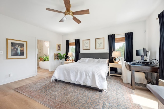 bedroom featuring ensuite bath, light wood-type flooring, baseboards, and ceiling fan