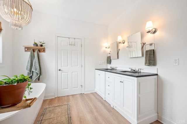 bathroom featuring double vanity, a freestanding bath, wood finished floors, and a sink