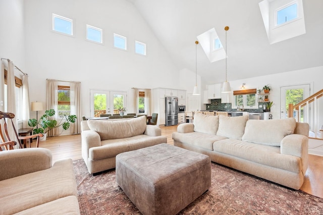 living room featuring a healthy amount of sunlight, light wood finished floors, high vaulted ceiling, and a skylight