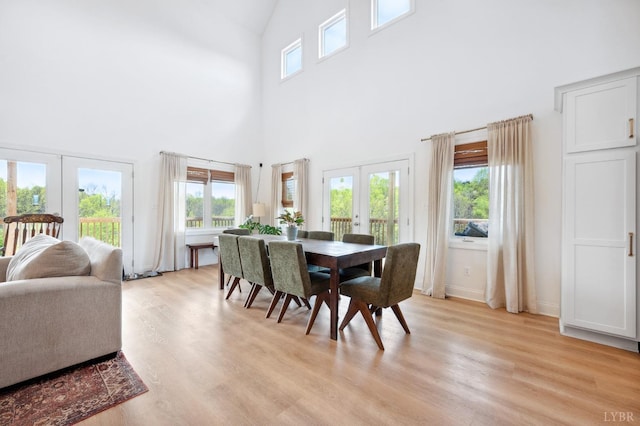 dining room featuring light wood finished floors, a high ceiling, and french doors