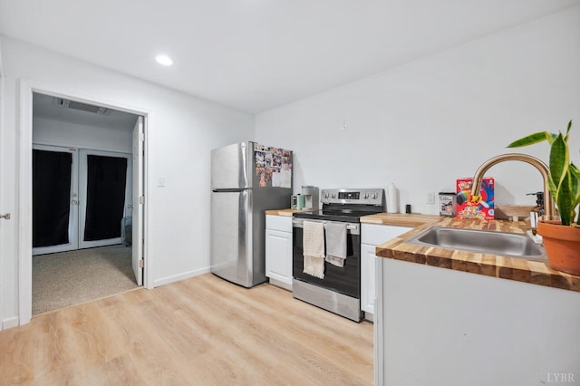 kitchen featuring a sink, white cabinets, visible vents, butcher block countertops, and appliances with stainless steel finishes