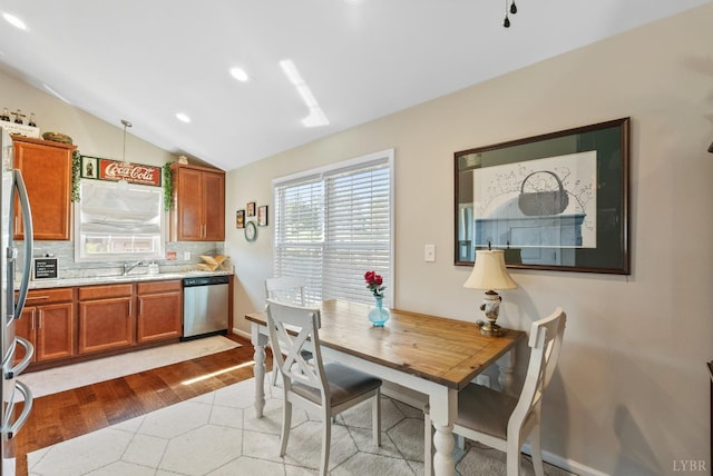 255 Traverse Dr, Evington, VA 24550 - kitchen with stainless steel dishwasher, brown cabinets, light countertops, lofted ceiling, and light wood-style floors