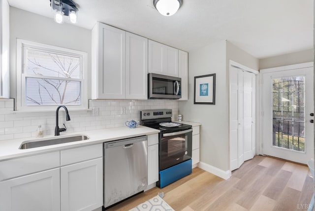 442 W King St, Bedford, VA 24523 - kitchen with tasteful backsplash, a sink, stainless steel appliances, light wood-style flooring, and white cabinetry