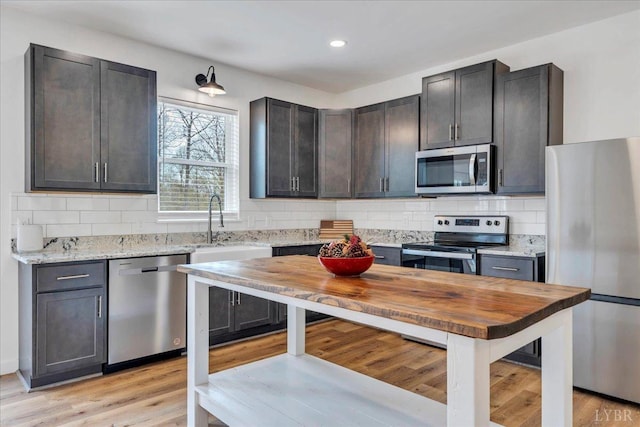 9900 Stonewall Rd, Appomattox, VA 24522 - kitchen with light stone counters, a sink, light wood-style flooring, backsplash, and appliances with stainless steel finishes