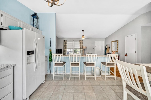 3783 Praline Pl, Roanoke, VA 24012 - kitchen with white fridge with ice dispenser, vaulted ceiling, a kitchen breakfast bar, white cabinets, and decorative light fixtures
