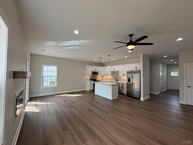 kitchen featuring stainless steel appliances, a kitchen island, baseboards, recessed lighting, and white cabinets