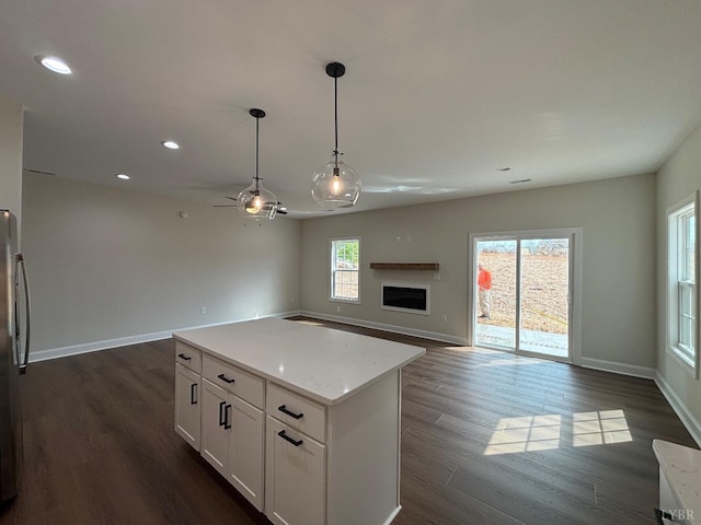 kitchen featuring open floor plan, white cabinetry, dark wood-type flooring, baseboards, and recessed lighting