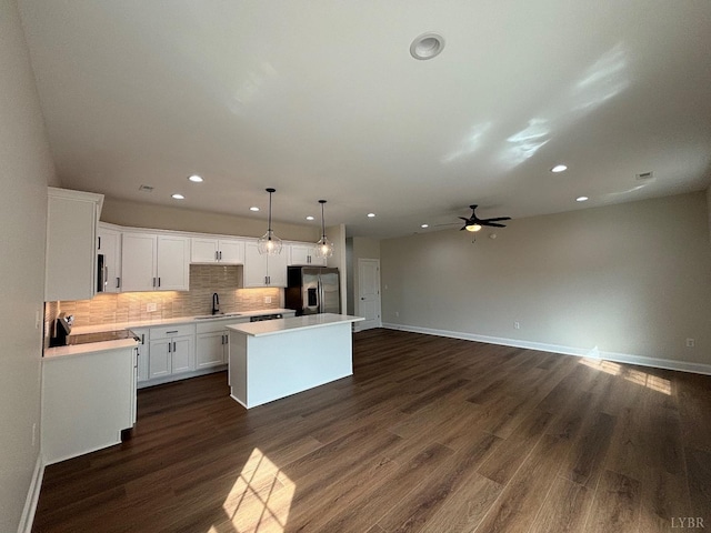 kitchen with stainless steel fridge with ice dispenser, a sink, a kitchen island, tasteful backsplash, and ceiling fan