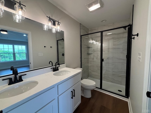 bathroom featuring wood finished floors, a shower stall, toilet, and double vanity