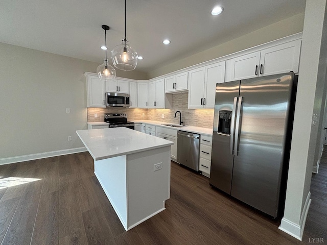 kitchen featuring stainless steel appliances, a sink, backsplash, a center island, and white cabinetry