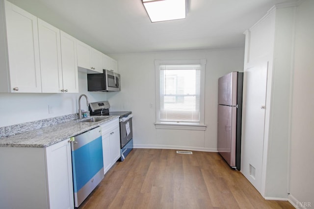 1518 14th St, Lynchburg, VA 24501 - kitchen featuring appliances with stainless steel finishes, wood finished floors, white cabinetry, and light stone countertops