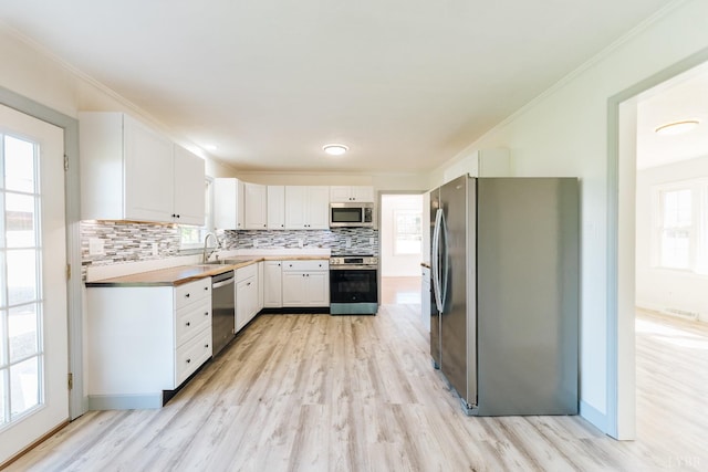 3677 Grit Rd, Hurt, VA 24563 - kitchen featuring stainless steel appliances, white cabinetry, decorative backsplash, crown molding, and light wood-type flooring
