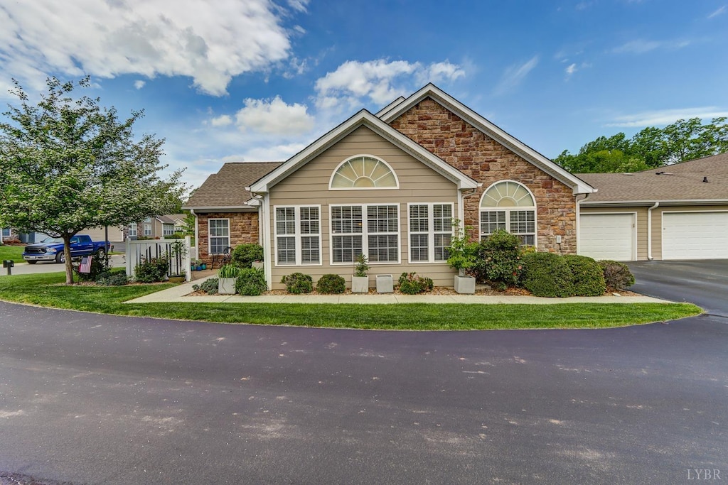 ranch-style house with a garage, driveway, and stone siding