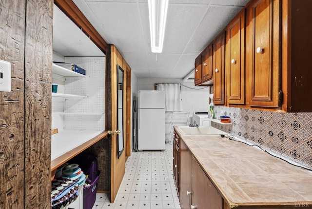 119 Adams Dr, Lynchburg, VA 24502 - kitchen with freestanding refrigerator, light flooring, tile countertops, brown cabinets, and a drop ceiling