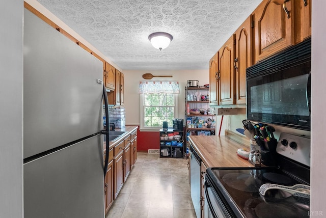 119 Adams Dr, Lynchburg, VA 24502 - kitchen with stainless steel appliances, brown cabinets, a textured ceiling, light tile patterned floors, and a sink