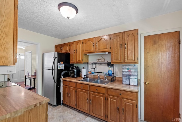 119 Adams Dr, Lynchburg, VA 24502 - kitchen with a sink, freestanding refrigerator, light countertops, brown cabinetry, and a textured ceiling