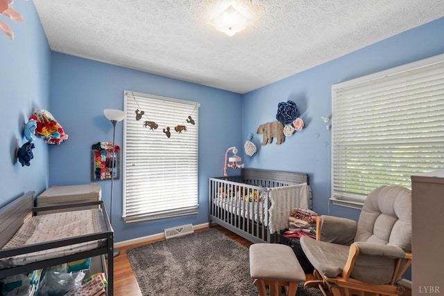 119 Adams Dr, Lynchburg, VA 24502 - bedroom featuring wood finished floors, a crib, a textured ceiling, and baseboards