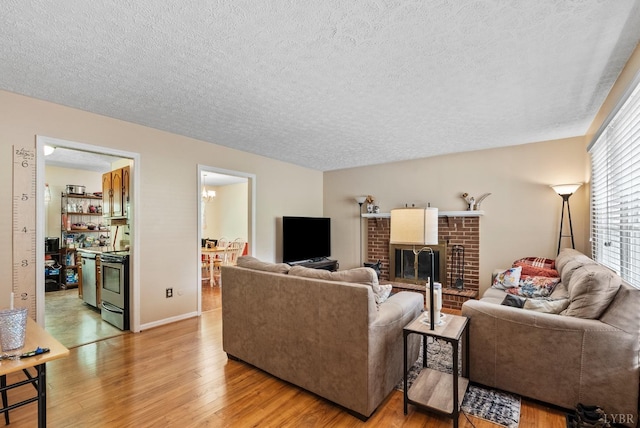 119 Adams Dr, Lynchburg, VA 24502 - living area with a textured ceiling, light wood-type flooring, a brick fireplace, and baseboards