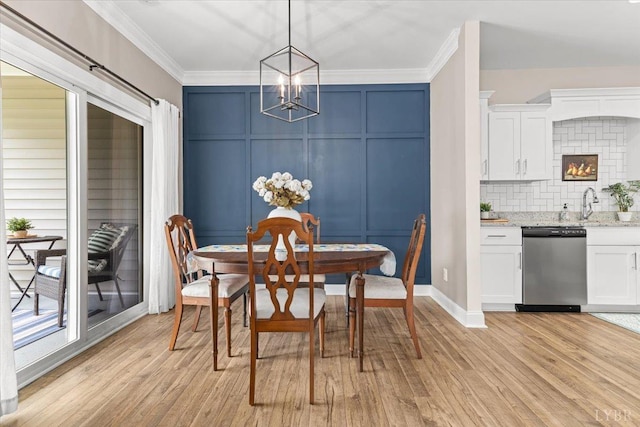 dining room with baseboards, a notable chandelier, ornamental molding, a decorative wall, and light wood-style flooring