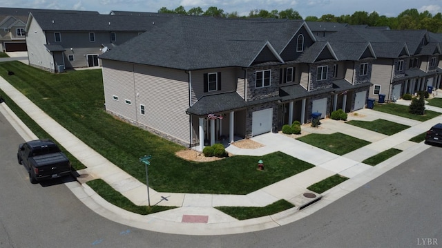 view of front of home featuring driveway, a residential view, a garage, a front lawn, and stone siding