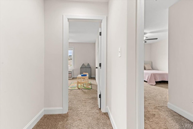 hall with baseboards and light carpet