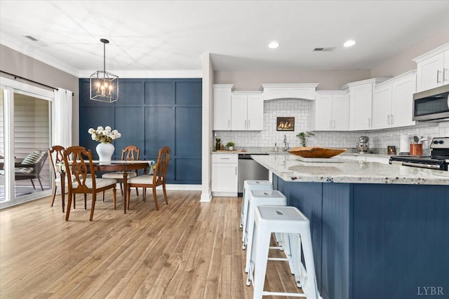 kitchen featuring white cabinets, stainless steel appliances, visible vents, and backsplash