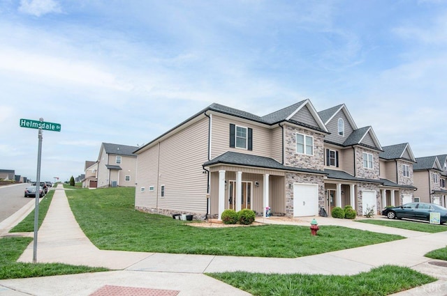 craftsman-style home featuring a residential view, an attached garage, stone siding, a front yard, and driveway