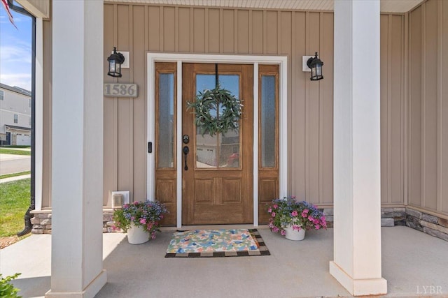 view of exterior entry with covered porch and board and batten siding