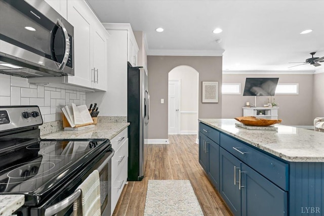 kitchen featuring blue cabinetry, crown molding, appliances with stainless steel finishes, arched walkways, and white cabinets