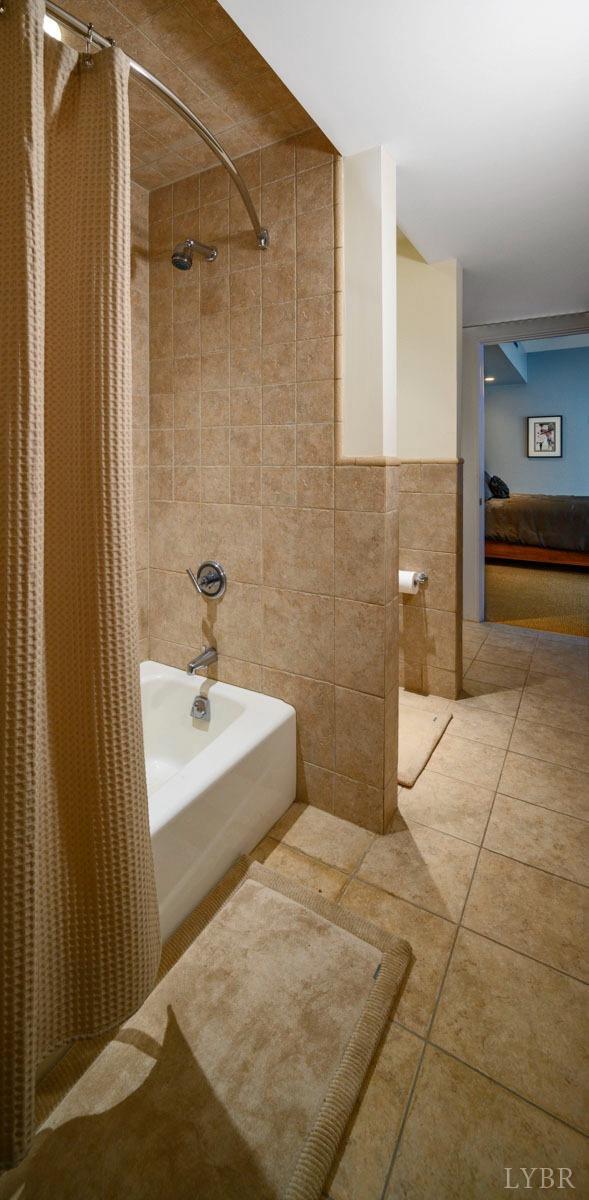 1209 Sycamore Creek Dr, Goode, VA 24556 - bathroom featuring tile patterned floors, tile walls, and shower / bathtub combination with curtain
