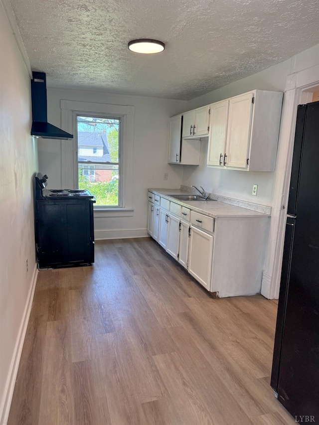 1305 Campbell Ave, Lynchburg, VA 24501 - kitchen with freestanding refrigerator, wall chimney exhaust hood, a sink, a textured ceiling, and light wood-style flooring