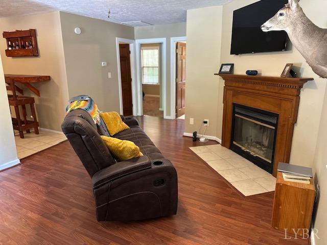 301 Gooseneck Ct, Forest, VA 24551 - living room with wood finished floors, a fireplace with flush hearth, baseboards, and a textured ceiling