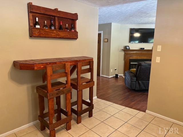 301 Gooseneck Ct, Forest, VA 24551 - dining room with light tile patterned flooring, baseboards, a fireplace, and a textured ceiling