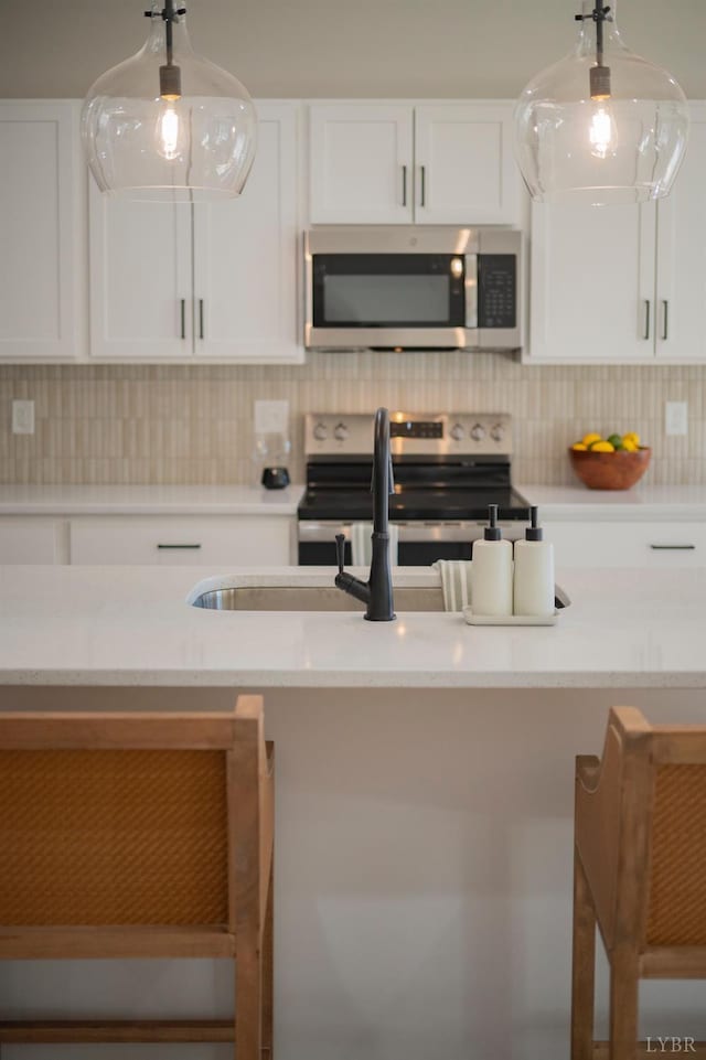 128 Brenleigh Ct Unit 108, Lynchburg, VA 24501 - kitchen with stainless steel appliances, white cabinets, backsplash, a kitchen breakfast bar, and light stone countertops